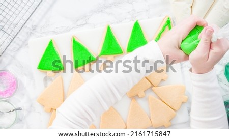 Flat lay. Stp by step. Icing Christmas tree-shaped sugar cookies with green royal icing.