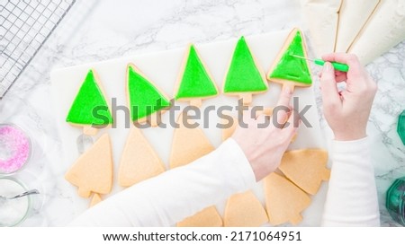 Flat lay. Stp by step. Icing Christmas tree-shaped sugar cookies with green royal icing.