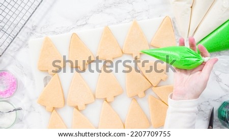 Flat lay. Stp by step. Icing Christmas tree-shaped sugar cookies with green royal icing.