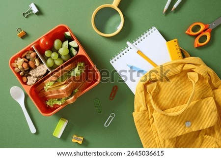 Flat lay of a student's daily items, including a nutritious bento lunch, stationery, and a yellow corduroy backpack