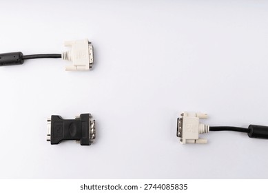 A flat lay studio shot showcasing two DVI-D cables with their white connectors, alongside a black DVI-I to DVI-D adapter. The items are arranged on a clean white background, illuminated with soft, even lighting, highlighting their details. This image represents various options for digital video display connectivity in computer setups.