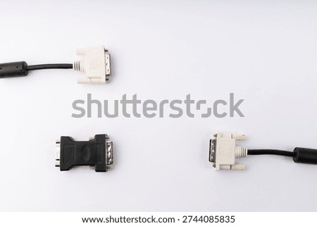 A flat lay studio shot showcasing two DVI-D cables with their white connectors, alongside a black DVI-I to DVI-D adapter. The items are arranged on a clean white background, illuminated with soft, even lighting, highlighting their details. This image represents various options for digital video display connectivity in computer setups.