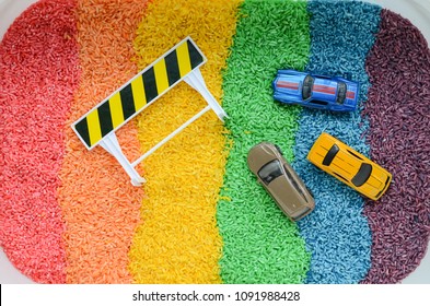 flat lay style photo of a bin of colorful rice and car toys with bright colors and texture, ready for child's sensorial play
