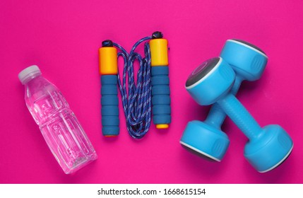 Flat lay style sport concept. Dumbbells, jump rope, bottle of water. Sports equipment on pink background. Top view - Shutterstock ID 1668615154