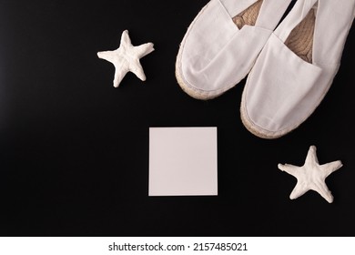 Flat Lay Of Summer And Beach Holiday. Starfish, White Espadrilles, White Letterhead In Black Background. Concept Of Travel Or Vacation Holidays.