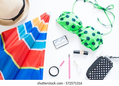 Flat Lay Of Summer Fashion With Green Color Swimsuit, Colorful Beach Umbrella And Girl Accessories On White Background