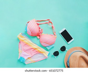 Flat Lay Of Summer Items With Colorful Bikini, Sunglasses , Hat And Smartphone On Green Background, Copy Space 