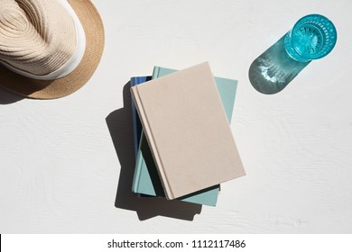 Flat Lay Of Sun Hat With A Stack Of Books And A Glass Of Water