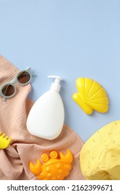 Flat Lay Sunscreen Lotion Bottle Mockup For Kids, Sunglasses, Sand Molds, Panama Hat, Towel On Blue Background. Sun Safety For Children And Babies Concept.