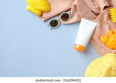 Flat Lay Sunscreen Tube Mockup For Kids And Babies, Sunglasses, Panama Hat, Towel, Sand Molds On Blue Background. Sun Safety, Infant Sun Protection Concept.