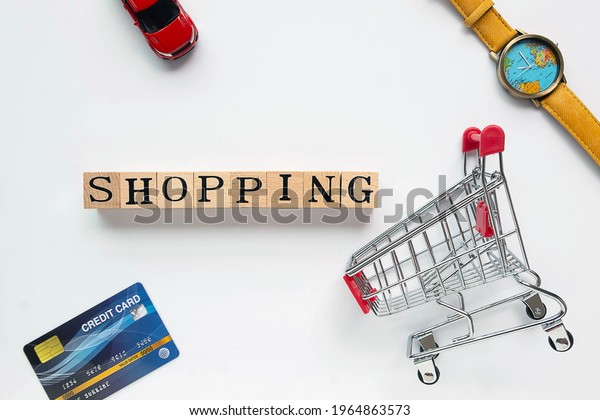 Flat lay Supermarket trolley,credit\
card,car,\
Wrist watch and wood text as shopping word on clear \
background.\
for shopping\
concept.