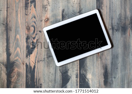 Flat lay of tablet with black screen on wooden vintage style background. Modern device on old wooden background top view. Contrast between new technology and ancient backdrop. Copy space