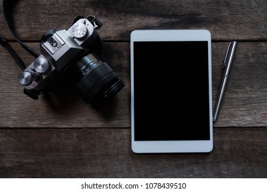 flat lay of tablet and camera on wood background