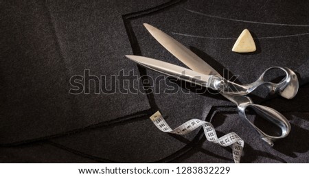 Flat lay tailor scissors,   black fabric , tape measure centimeter on black fabric background