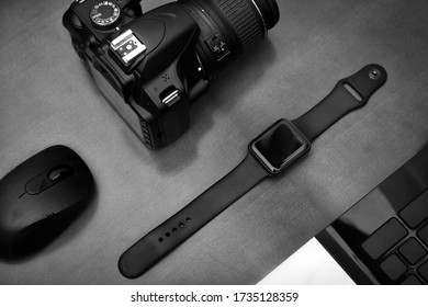Flat lay of techno items for modern worker with smartwatch mobile phone and dslr camera on wooden table.