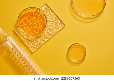 Flat lay of a test tube with spiral pipe inside and several petri dishes filled with orange liquid decorated on orange background. Copy space for text adding