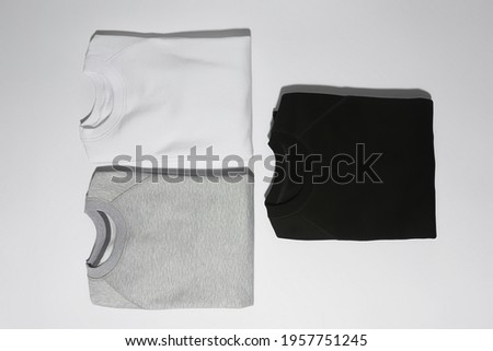 Flat lay of three perfectly folded monochrome sweatshirts gray, black and white isolated over white background. Clothes, fashion, retail concept. Horizontal shot