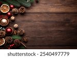 Flat lay top down view of christmas theme decorations and decor on a dark wood table natural objects brown paper packages tied with jute string pinecones and snowflakes and green pine boughs