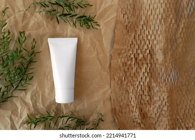 flat lay or top view above of packshot facial skincare white tube bottle product with blank label decoration  Ellwood's Gold Conifer green leaves brown color creased paper minimal background space