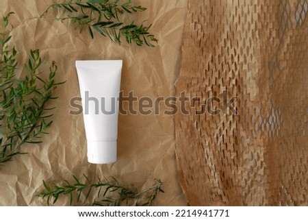 flat lay or top view above of packshot facial skincare white tube bottle product with blank label decoration  Ellwood's Gold Conifer green leaves brown color creased paper minimal background space