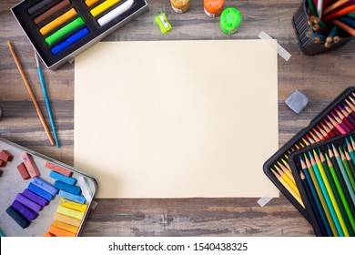 Flat Lay Top View Of Art Workplace, Wooden Table With Colored Pencils, Paper And Crayon Pastel Chalks