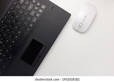 Flat lay, top view black laptop and white mouse on white office desk with copy space, workspace blank. Minimal desk concept.
