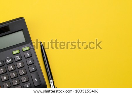 Flat lay or top view of black pen with calculator on vivid yellow background table with blank copy space, math, cost, tax or investment calculation.