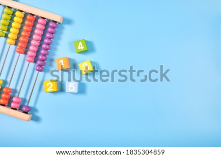 Flat lay, Top view of bright colored wooden bricks and abacus toy background with copy space for text, Numeral cubes with numbers 1 to 5 & colorful abacus, Child development, early math skills concept