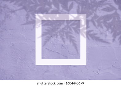 Flat lay top view of creative copyspace with paper frame and tropical leaves palm shadow on very peri violet color background.