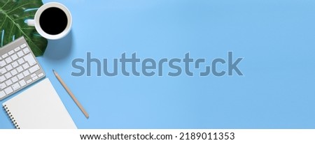 Flat lay of top view desk work table with Coffee computer notebook and pencil work space in minimal blue tone concept includes copyspace for add text or graphic
