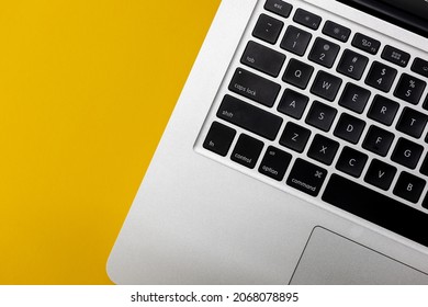 Flat lay, top view of Laptop computer keyboard on a bright yellow background. Closeup macro aesthetic profile shot of keyboard. Work from home WFH workspace - angle 4