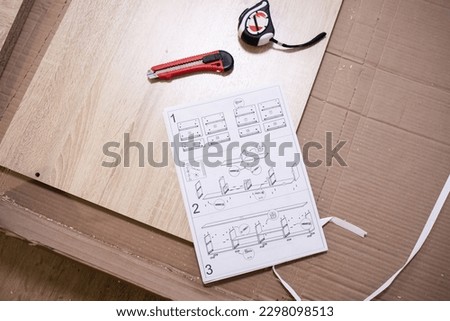 Flat lay, top view, mockup, copy space. Paper instructions for assembling furniture, schematic drawing, construction knife, home assemle work, tape measure. Repair, renovation. Working instructions 