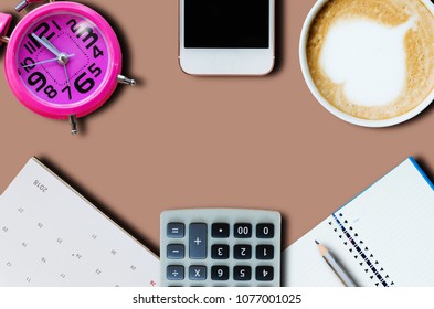 flat lay top view office desk Include coffee cup, smartphone, clock, calendar, calculator, notebook and pencil frame with copy space on brown background.