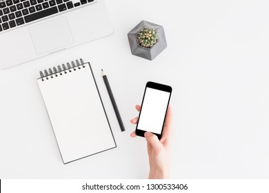 Flat lay, top view office table desk. Workspace with spiral notebook, keyboard, mobile, office supplies, pencil, green cactus, and coffee cup on white background