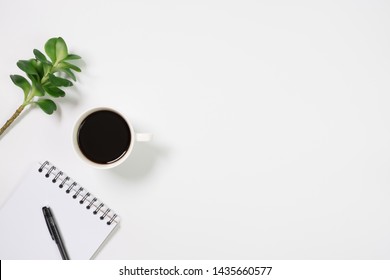 Flat Lay, Top View Office Table White Desk. Workspace With Blank Notepad, Pen And Green Leaf On White Background. Minimal Desk.