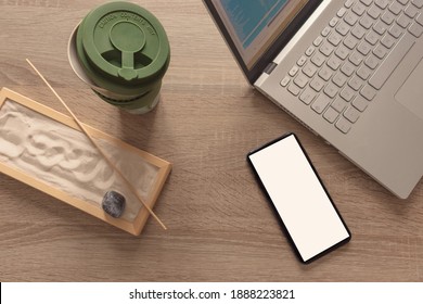 Flat Lay, Top View Of A Office Table Desk. Workshop Layout With Coffee Mug, Smartphone, Laptop, And Zen Garden On Wooden Background. Copy Space.