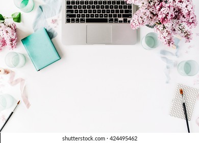 Flat lay, top view office table desk. Workspace with paintbrush, laptop, lilac flowers bouquet, spool with beige and blue ribbon, mint diary on white background. - Shutterstock ID 424495462