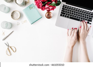 Flat lay, top view office table desk. Workspace with girl's hands, laptop, red roses bouquet, mint diary, coffee mug and golden scissors on white background.
