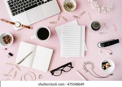 Flat lay, top view office table desk. feminine desk workspace with succulent, laptop, glasses, diary and golden clips on pink background.