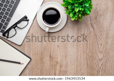 Flat lay, top view office table desk. Workspace with, laptop,office supplies, pencil, green leaf, and coffee cup on wood background.