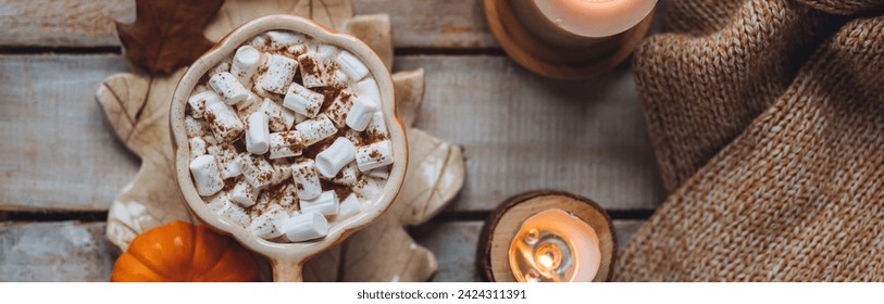 Flat lay top view. Spicy sweet fall hot drink: delicious pumpkin latte with cinnamon, marshmallow. Served in handmade artisan mug in shape of pumpkins, cozy home decor with candles, dry leaves banner - Powered by Shutterstock