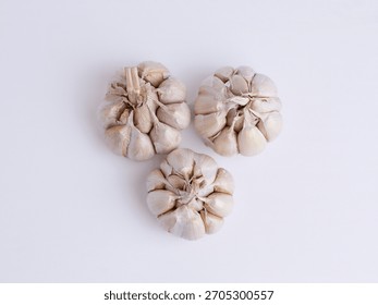 Flat lay top view of three fresh garlic bulbs isolated on white background. Spicy organic cooking ingredient concept.
