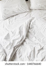 Flat lay, top view of white linen with sheet, blanket and two pillows. Minimal bed concept.