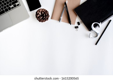 Flat lay, top view, white office desk Notebook computers, black pencils, black pens, metal letters and the black notebooks, Paper clips, wallet, pine cones, office desk layout ideas
