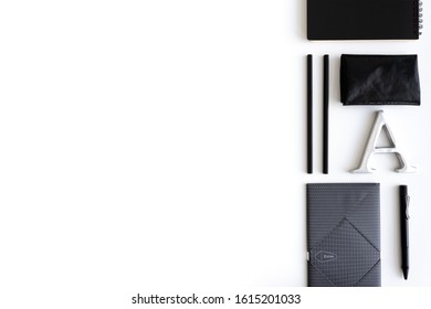 Flat lay, top view, white office desk Notebook computers, black pencils, black pens, metal letters and the black notebooks, Paper clips, wallet, pine cones, office desk layout ideas