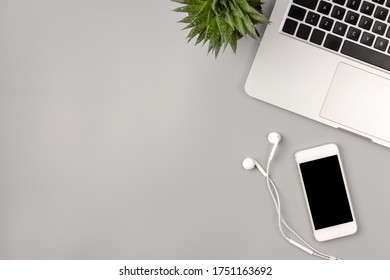 Flat lay, top view of working space, office desk. Workspace with laptop, smartphone and home plant on gray background