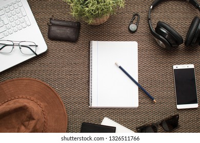 Flat lay. Top view of workspace. Travel or trip planning with notebook in the middle. Laptop mobile phone, wallet, headphones, notebook, pencil