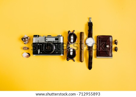 Flat lay traveler accessories on yellow background. Camera, watch, cigar, sunglasses. Top view travel or vacation concept. Summer background.