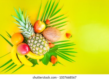Flat lay of tropical fruits on palm leaves. Pineapple, mango, banans, orange, apple and strawberries. Yellow background. Copy space. Horizontal. - Shutterstock ID 1037668567