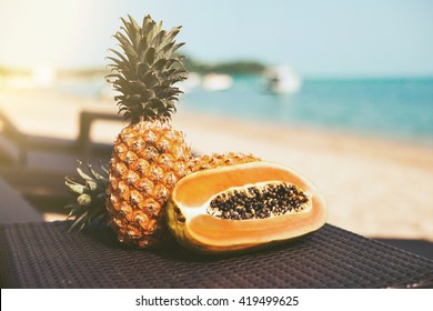 Flat Lay. Tropical fruits are on the rattan, plastic table on the beach, pineapple papaya, lighting effects, color toning, summer style - Powered by Shutterstock